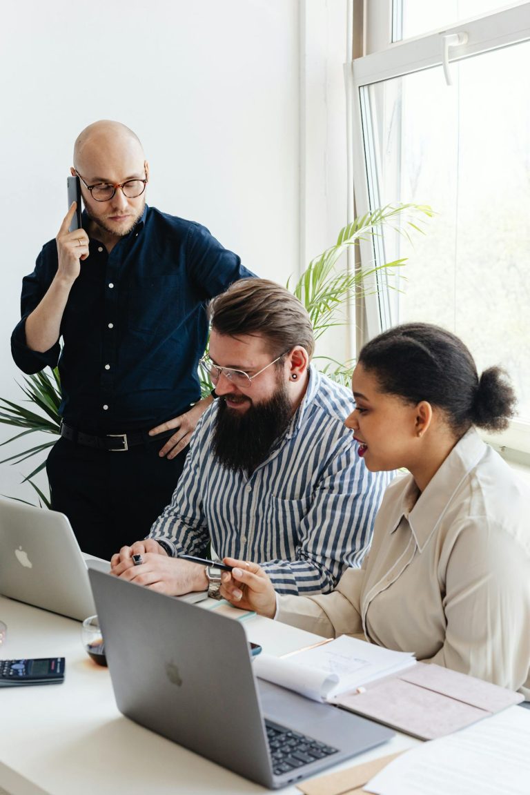 A diverse group of professionals engaged in a collaborative team meeting at a modern office with laptops and mobile phones.